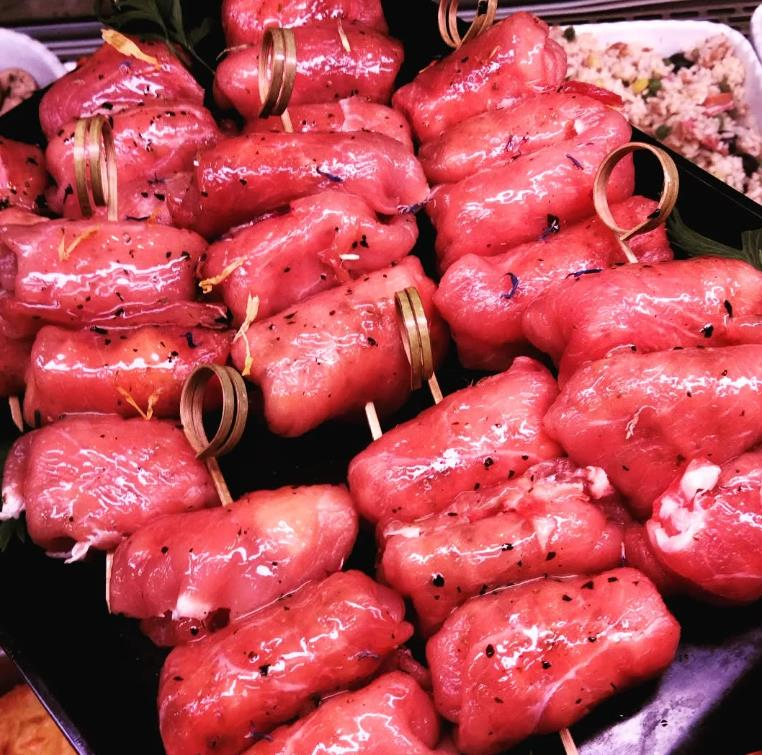 Un mazzo di spiedini di carne su un piatto nero