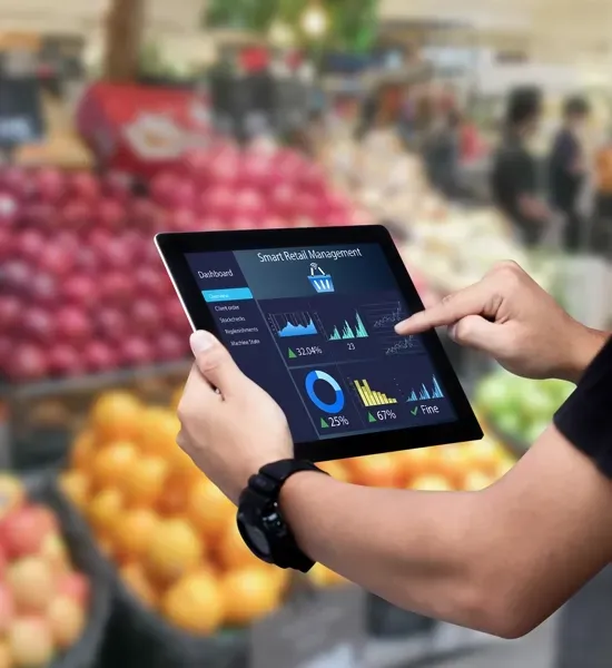 Person using a tablet displaying data analytics in a produce section of a grocery store.