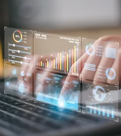 Hands typing on a laptop with holographic data charts overlaid.