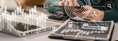 Person working on a laptop and using a phone with overlaid data visualizations.