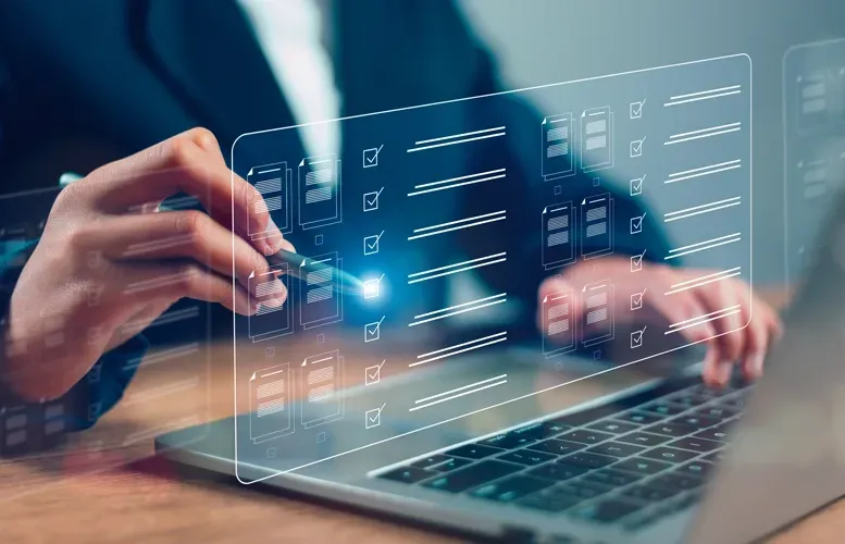 Person's hand using a stylus on a transparent digital survey form displayed over a laptop.