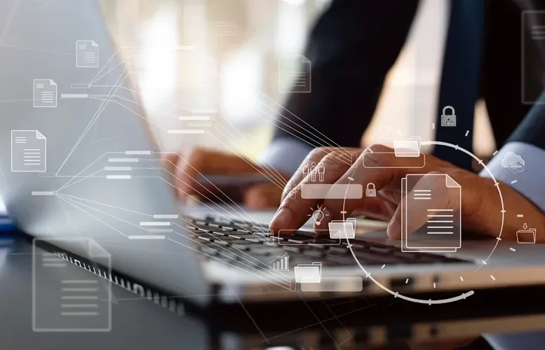 Hands typing on a laptop with overlaid digital document icons and network lines.