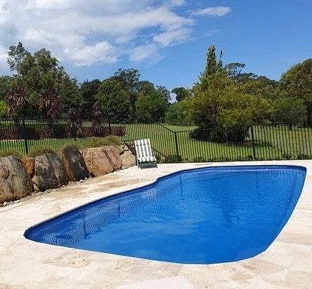 A Pool With A Lawn Chair And Fence - In Ground Pools in Nowra, NSW