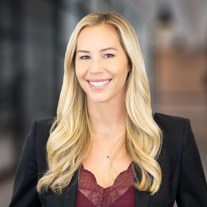 A woman wearing a black jacket and a red top is smiling for the camera.