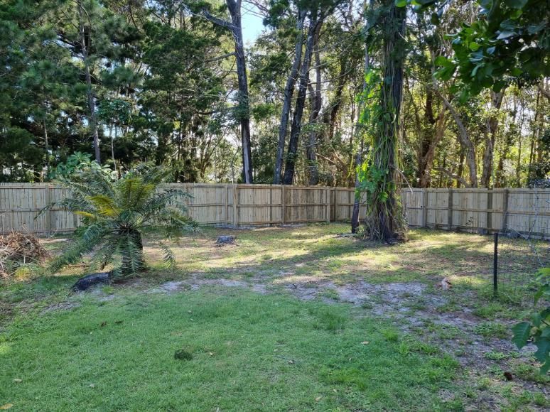 A Backyard with A Wooden Fence and Trees in The Background — Quality Fencing Solutions in Ballina, NSW