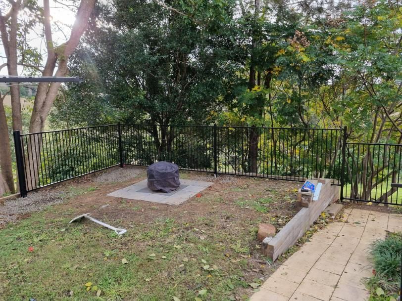 A Backyard with A Fence and A Fire Pit in The Middle of It — Quality Fencing Solutions in Ballina, NSW