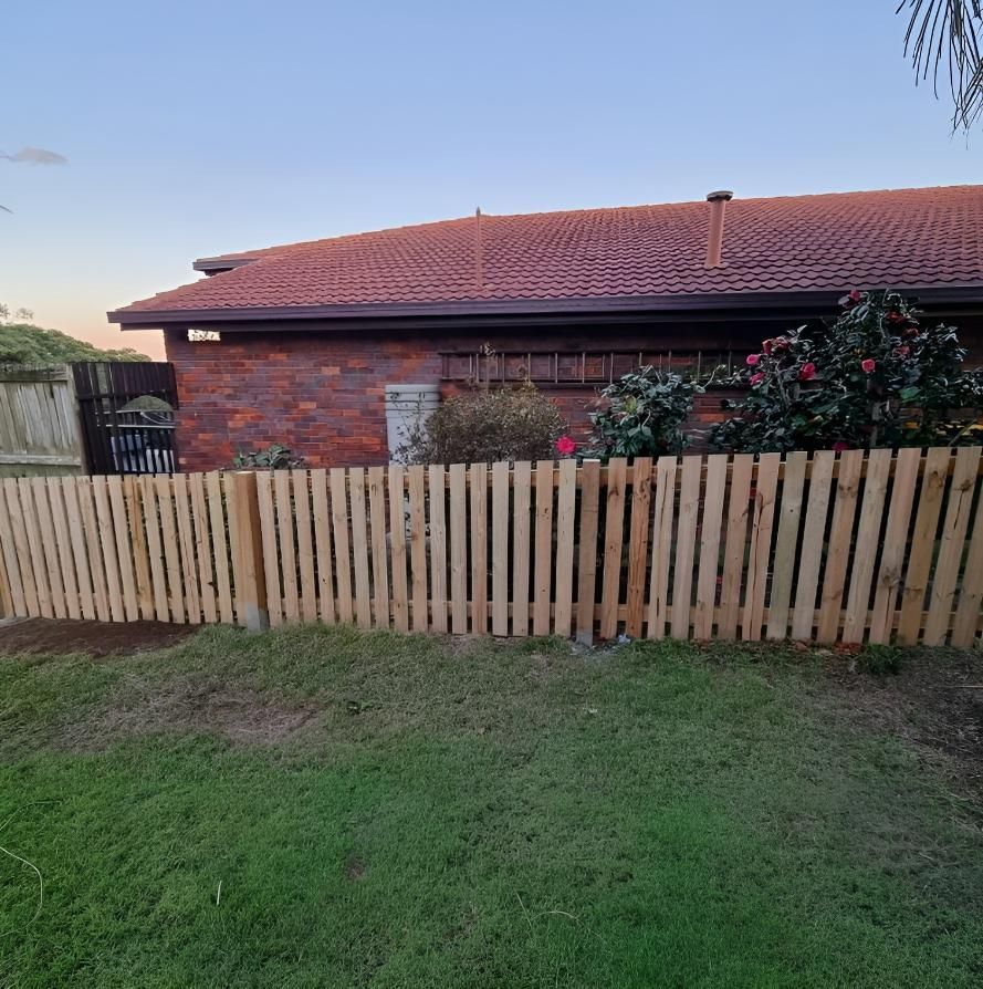 A Wooden Fence Is in Front of A Brick House — Quality Fencing Solutions in Ballina, NSW