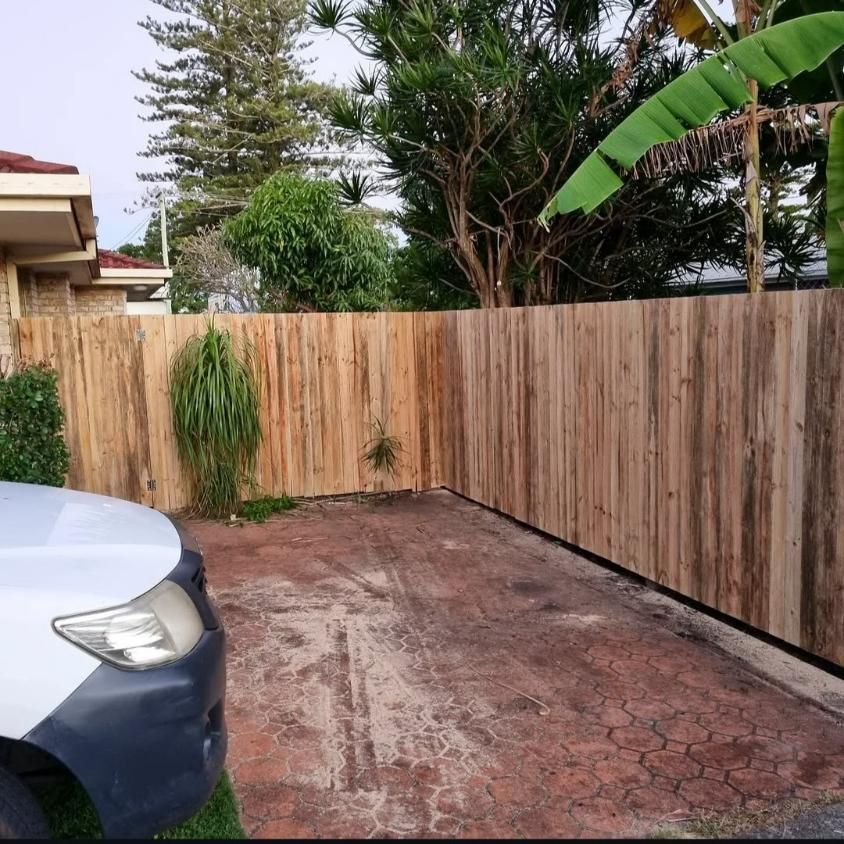 A White Car Is Parked in Front of A Wooden Fence — Quality Fencing Solutions in Ballina, NSW