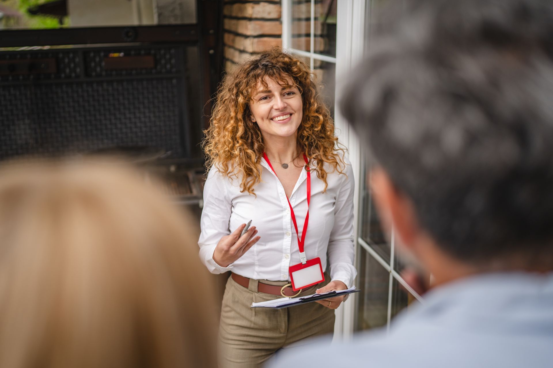 Real estate agent in white shirt talks to prospective buyers at a house entrance.