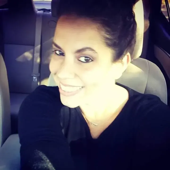 A woman is smiling while sitting in the back seat of a car