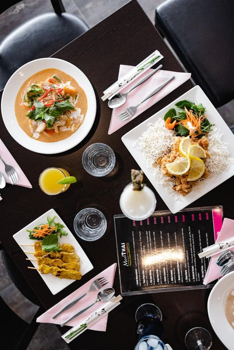 A Table Topped With Plates Of Food And Utensils — Mod Thai Nelson Bay In Nelson Bay, NSW