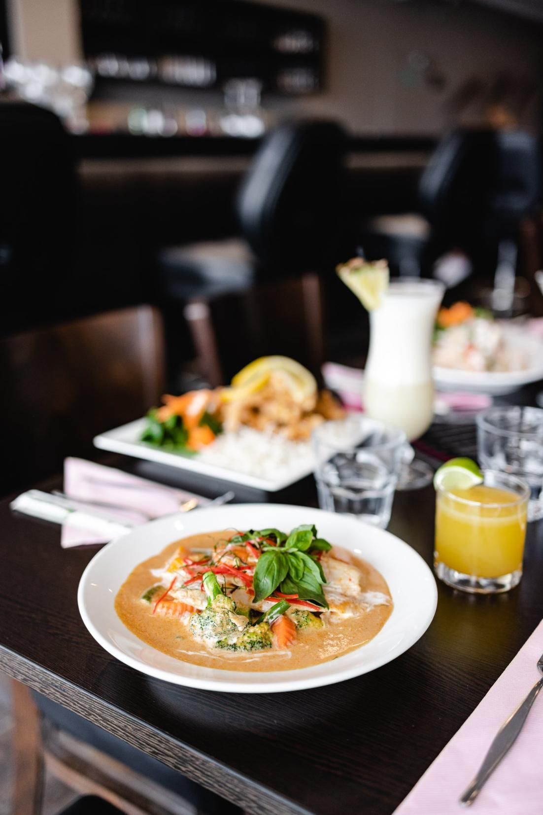 A Plate Of Food Is Sitting On A Table Next To A Drink — Mod Thai Nelson Bay In Nelson Bay, NSW