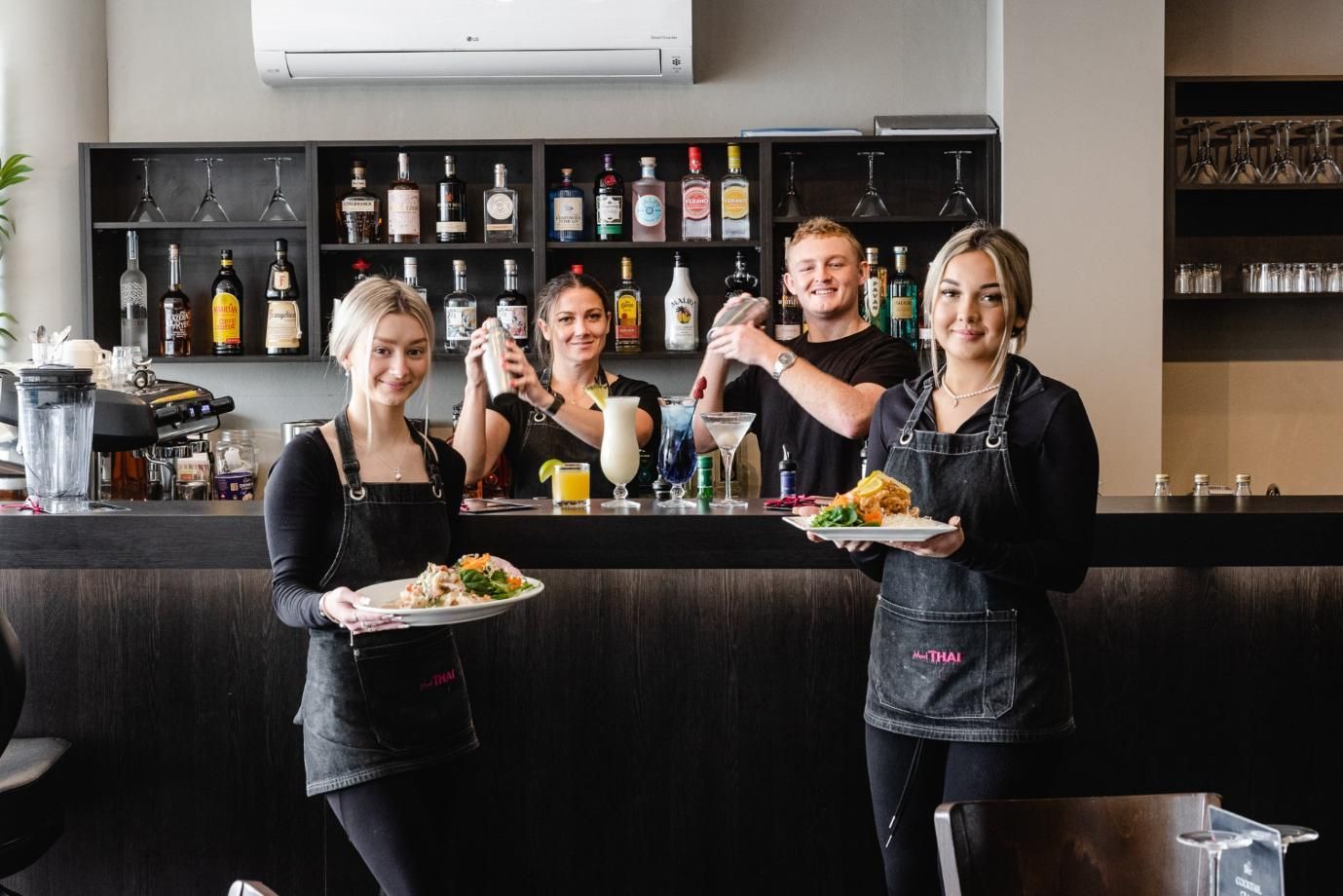 A Group Of People Are Standing In Front Of A Bar Holding Plates Of Food — Mod Thai Nelson Bay In Nelson Bay, NSW