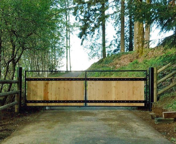 Raised garden beds beside a blue wire gate in a wooded outdoor area