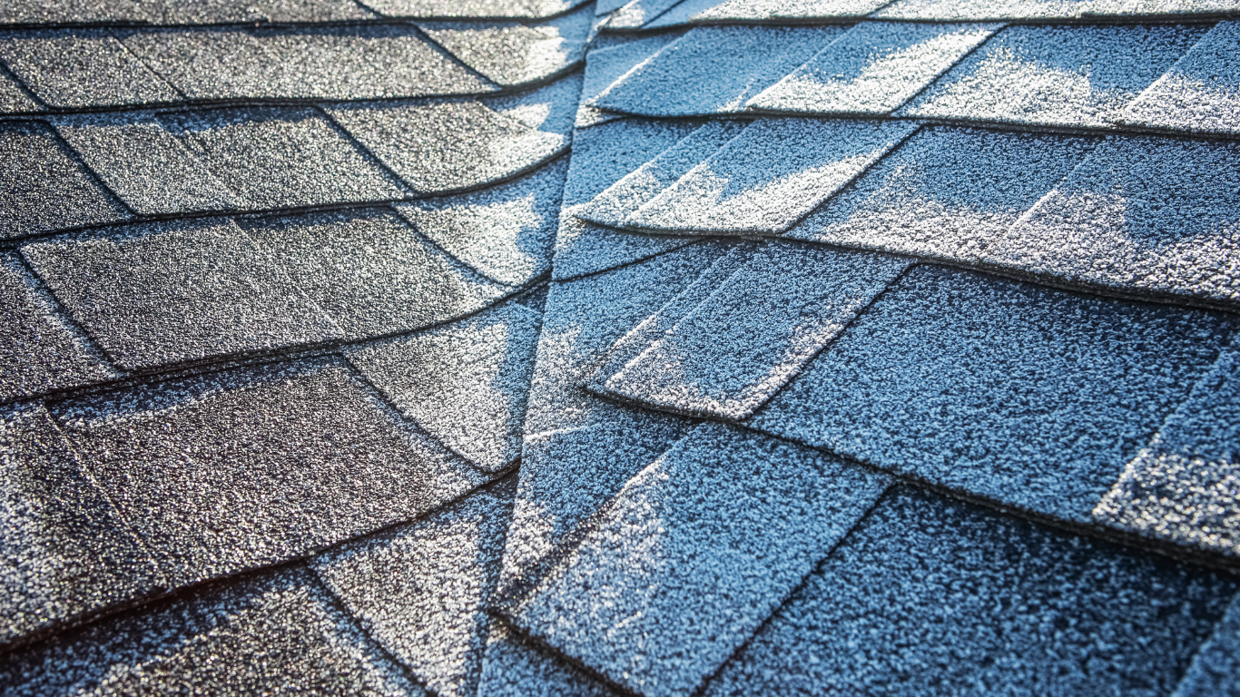A close-up view of a dark grey, corrugated metal roof with repeating wave patterns against a slightly cloudy sky.