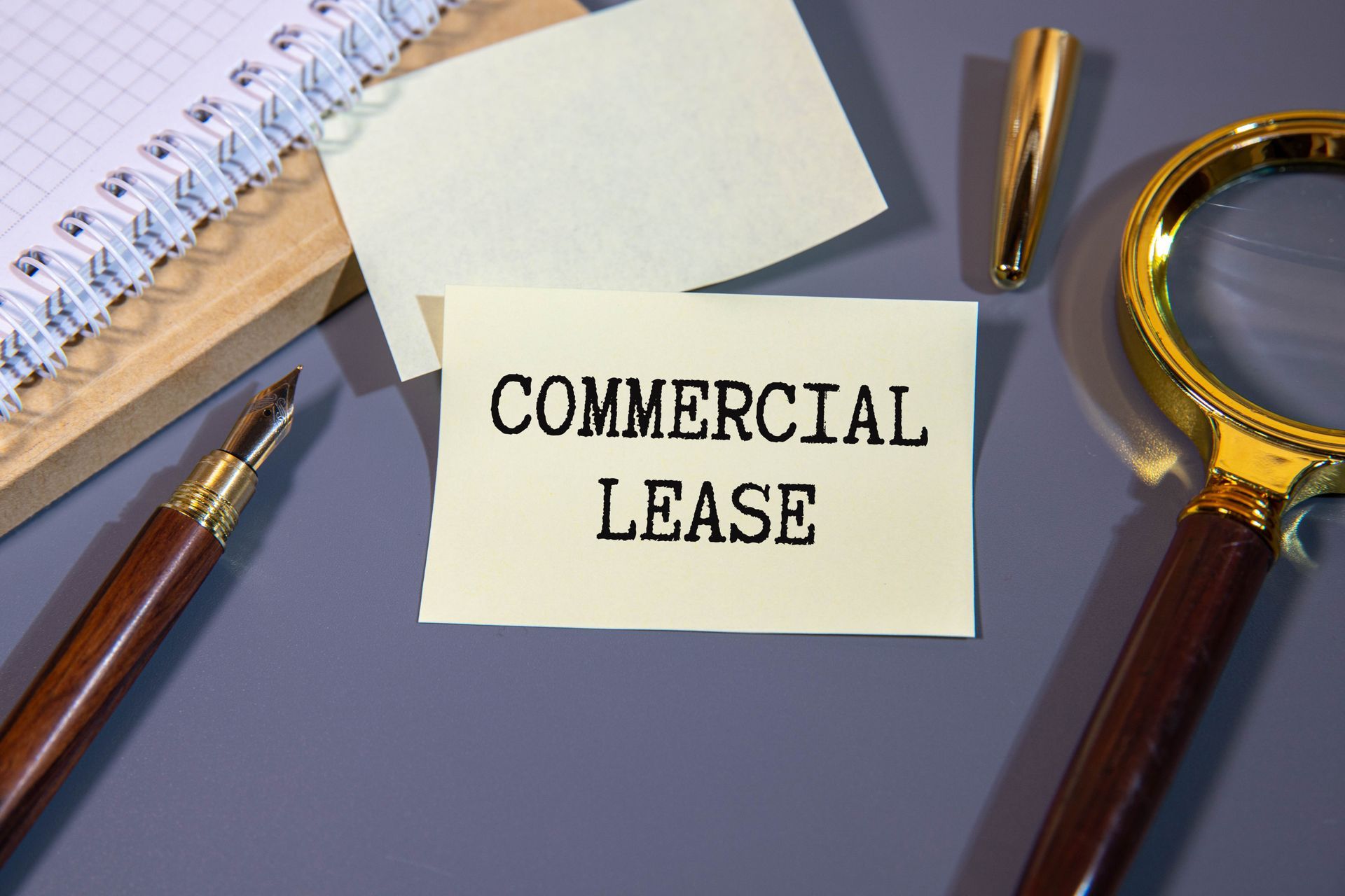 Commercial lease text written on a Post-it with a pen, notebook, and eyeglasses next to it. Commercial lease text written on a Post-it with a pen, notebook, and eyeglasses next to it.