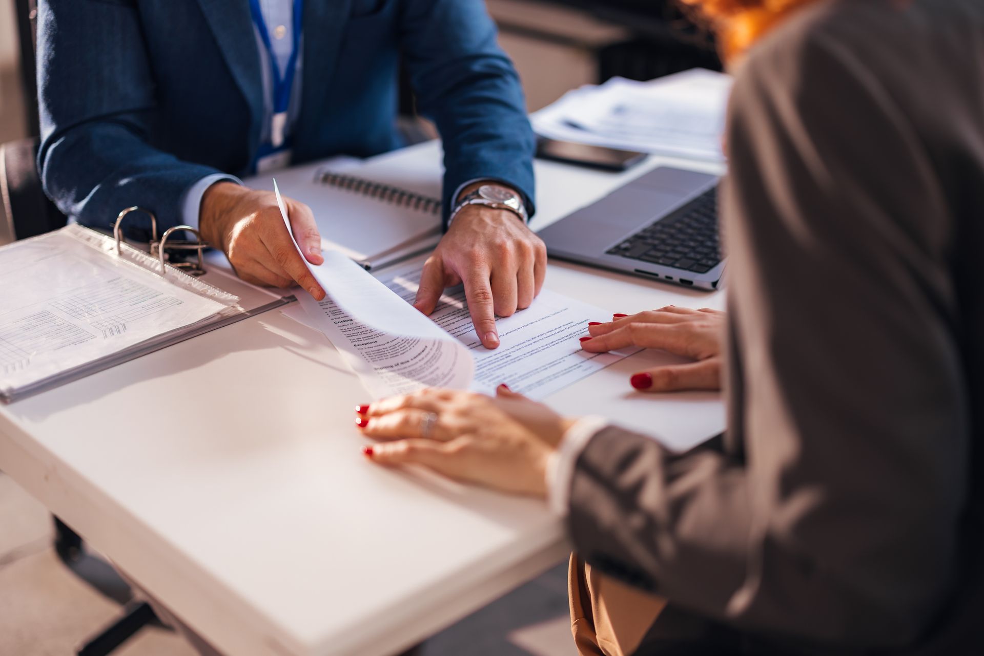 A business law lawyer is indicating to a client where to sign after reviewing business documents. A business law lawyer is indicating to a client where to sign after reviewing business documents.