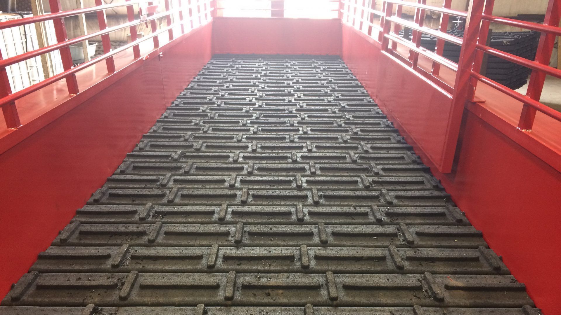 Red ramp with black textured surface, flanked by red railings.