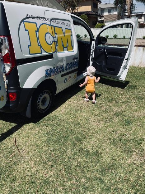 A Little Girl Is Standing In Front Of A Van With The Door Open — Illawarra Cleaning & Maintenance In Dapto, NSW