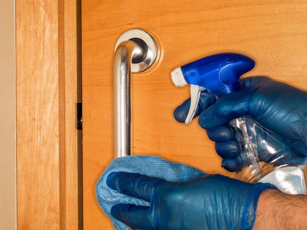 A Person Wearing Blue Gloves Is Cleaning A Door Handle — Illawarra Cleaning & Maintenance In Dapto, NSW