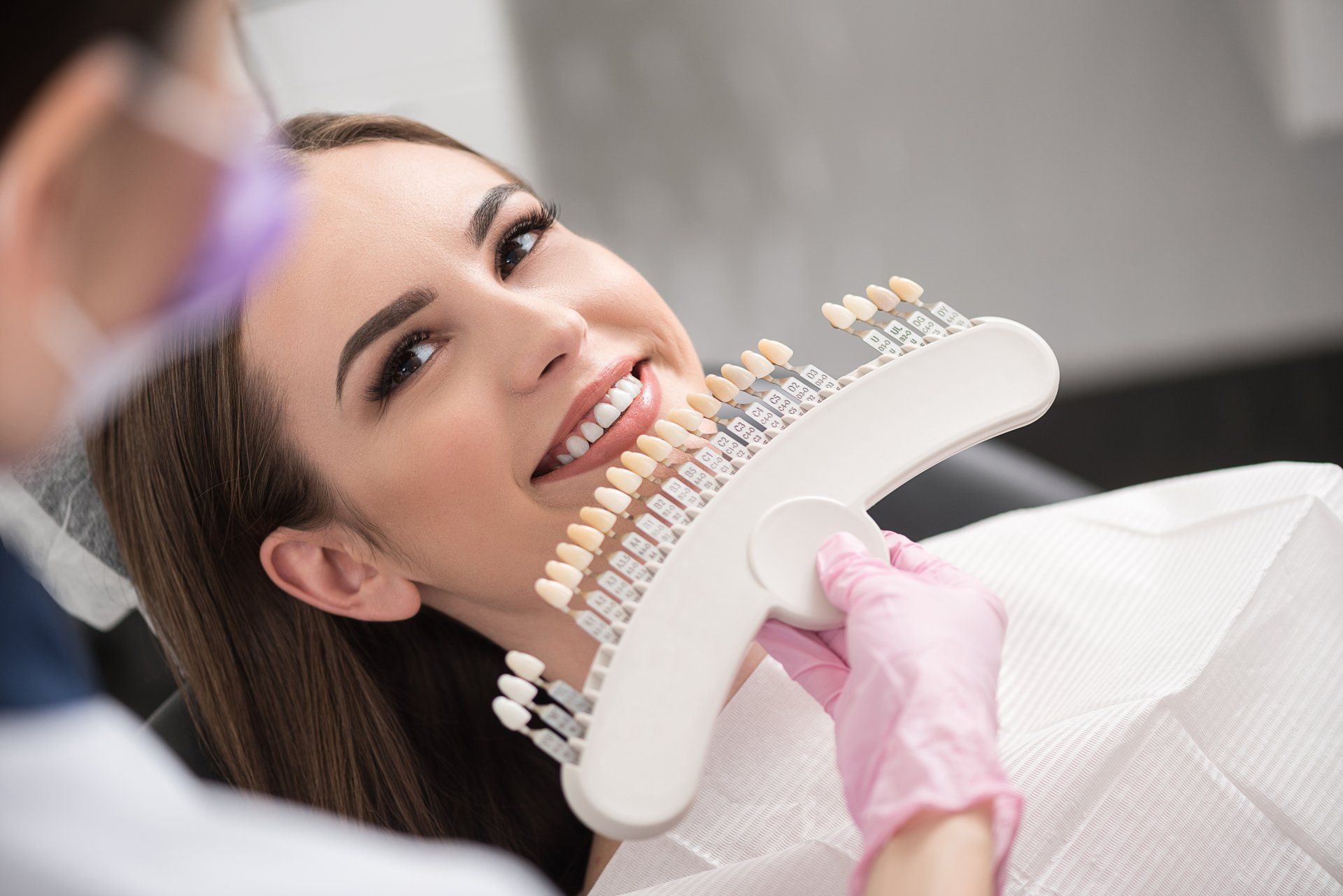 a woman is sitting in a dental chair while a dentist examines her teeth .