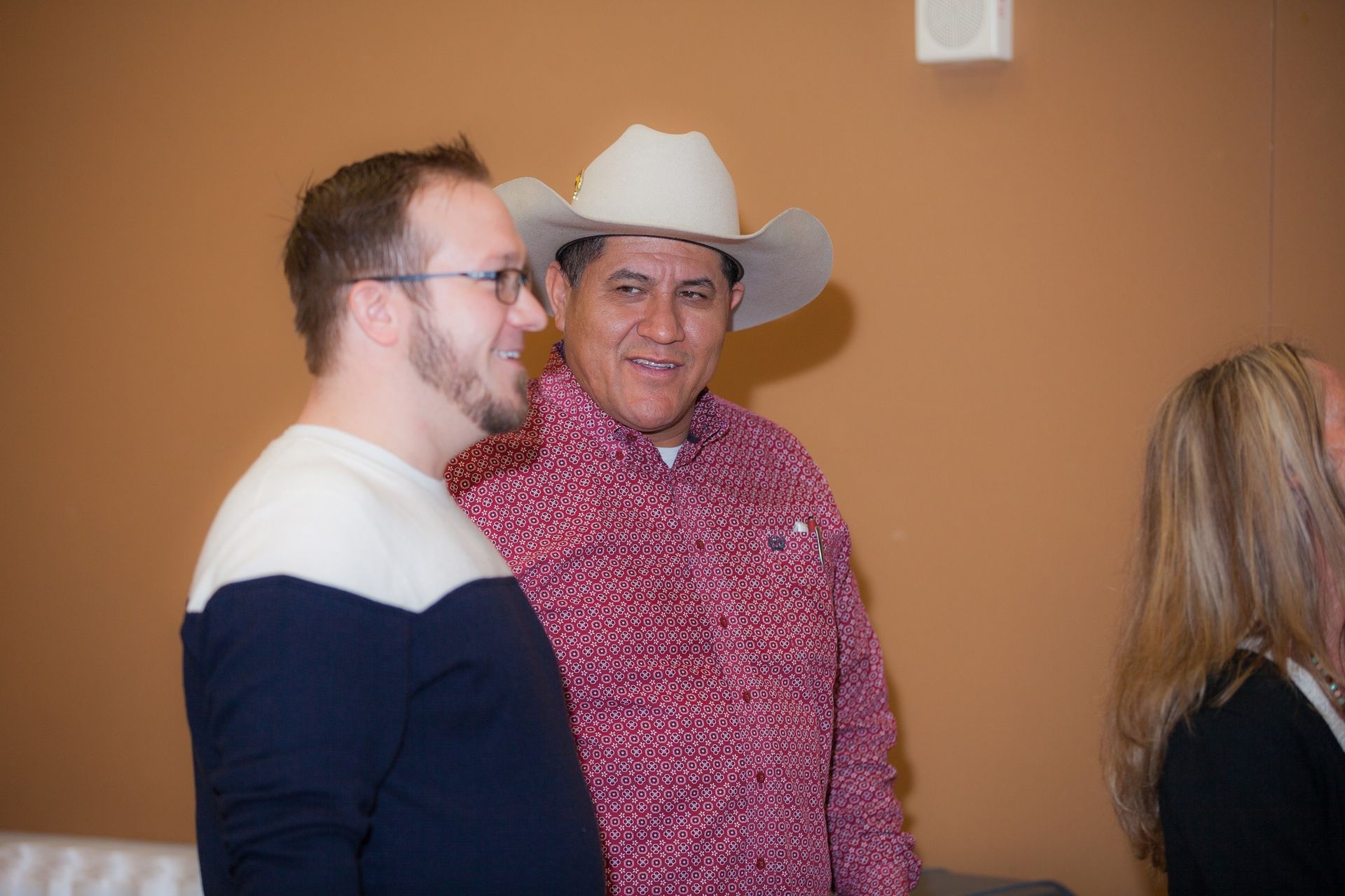 Two men in cowboy hats are standing next to each other in a room.