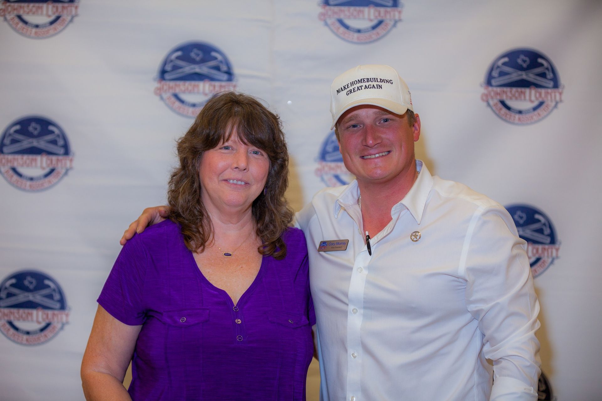 A man and a woman are posing for a picture . the woman is wearing a purple shirt.
