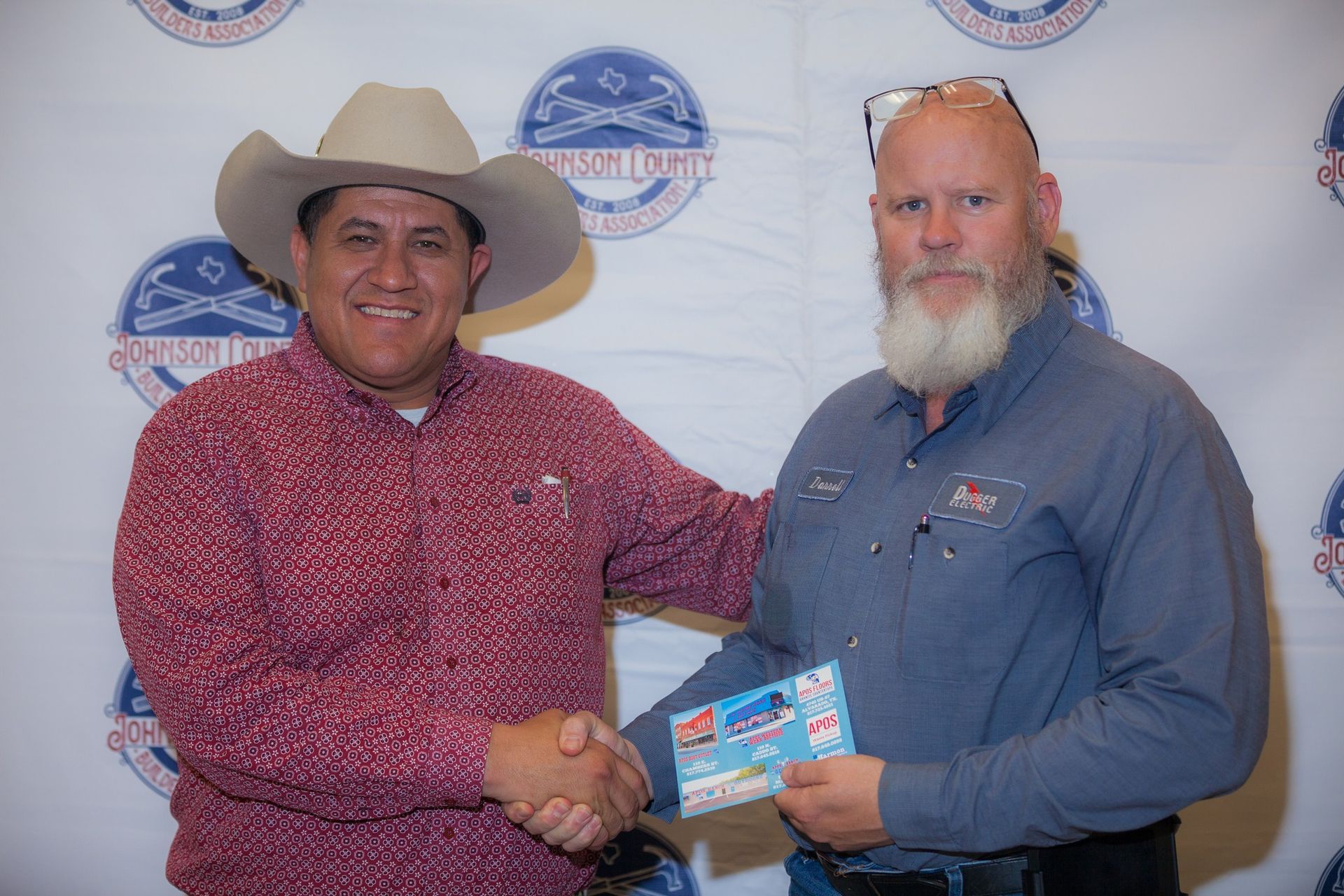 Two men are shaking hands and one of them is wearing a cowboy hat.