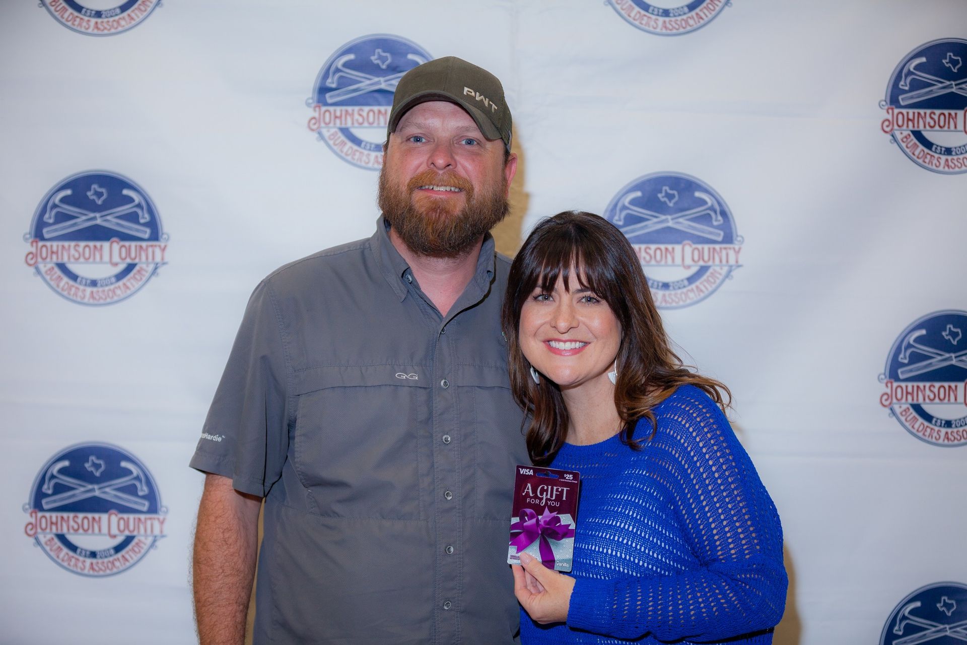 A man and a woman are posing for a picture . the woman is holding a gift.