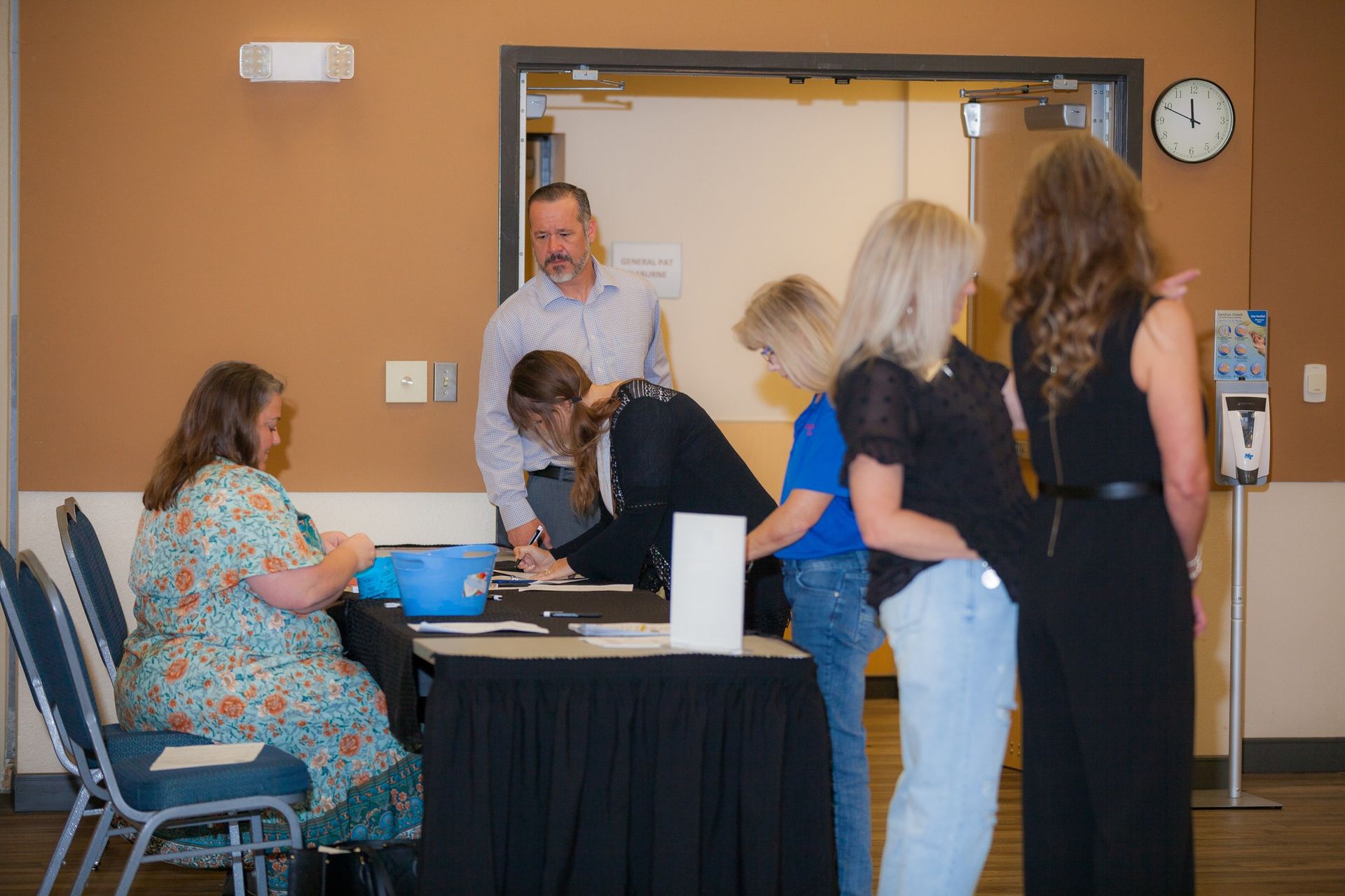 A group of people are standing around a table in a room.