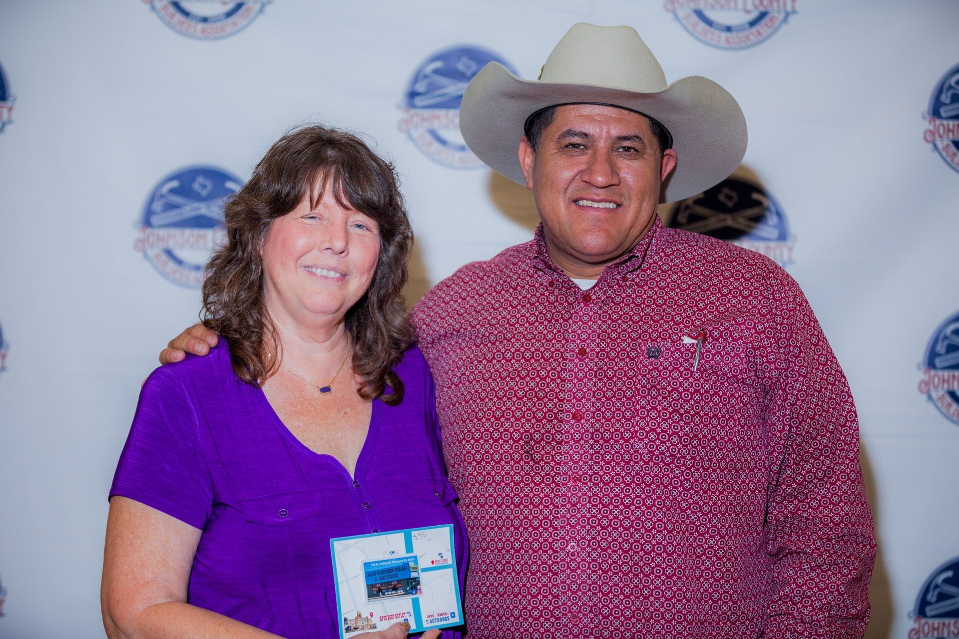 A man in a cowboy hat is standing next to a woman in a purple shirt.