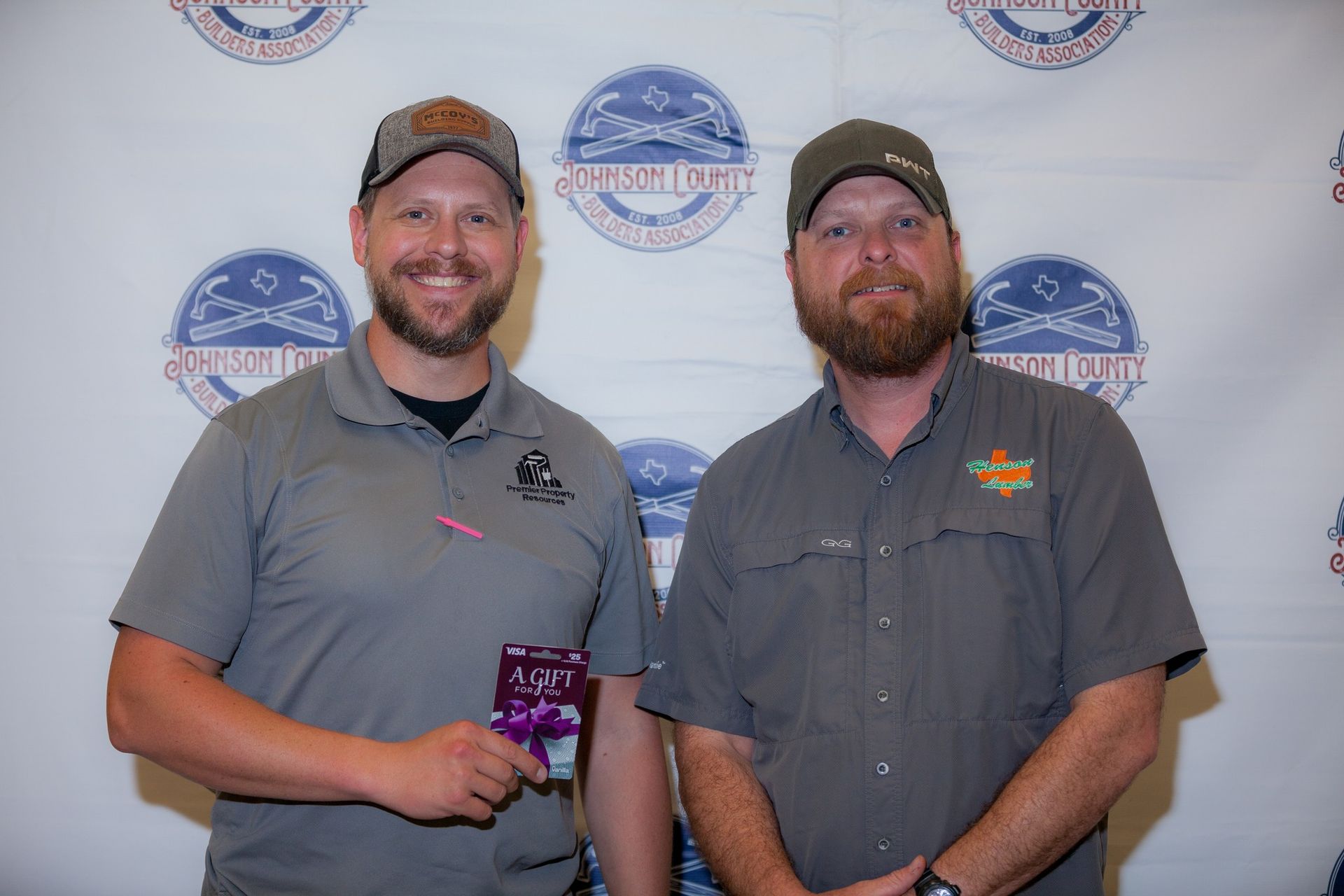 Two men are standing next to each other in front of a wall.
