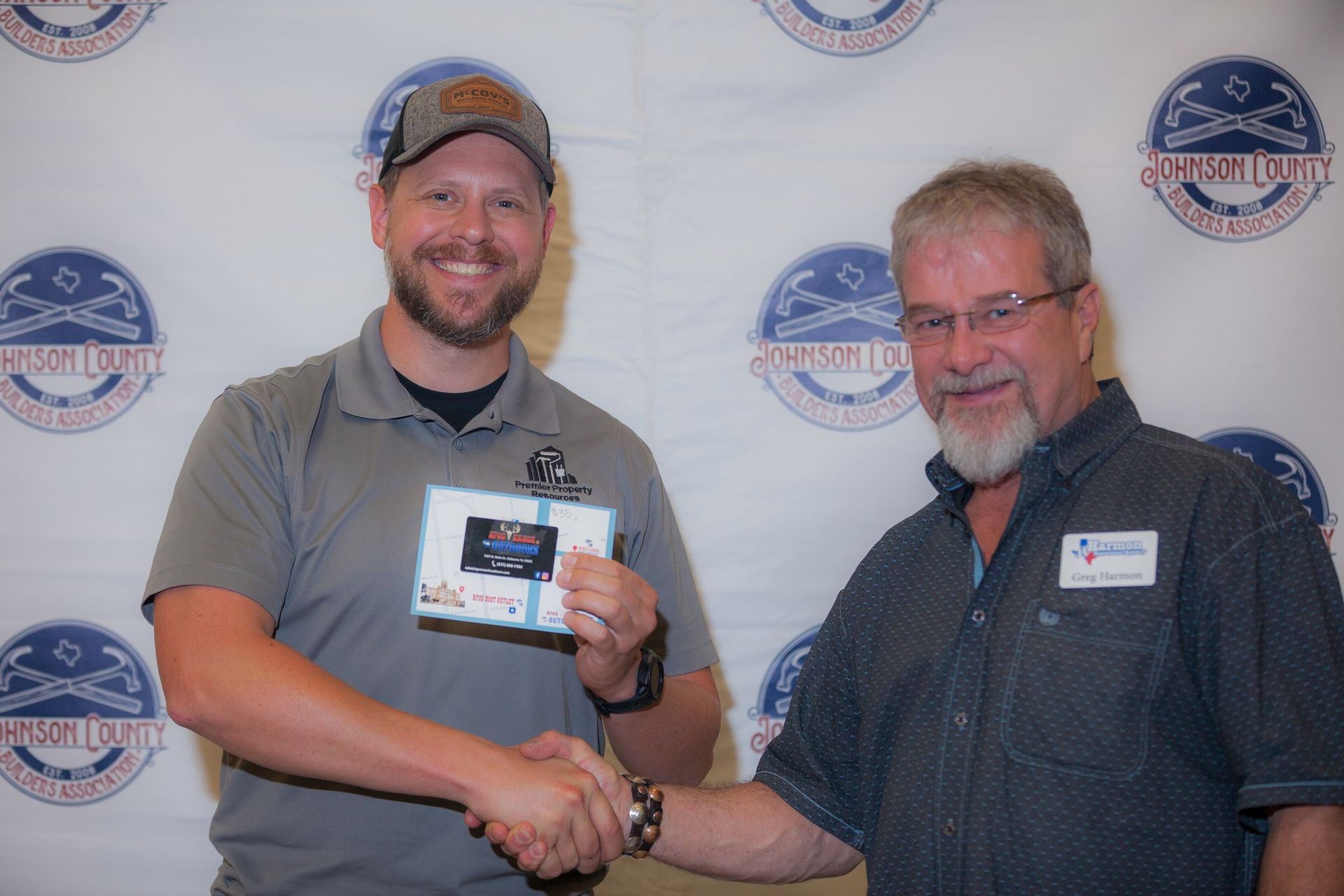 Two men are shaking hands and one of them is holding a card.