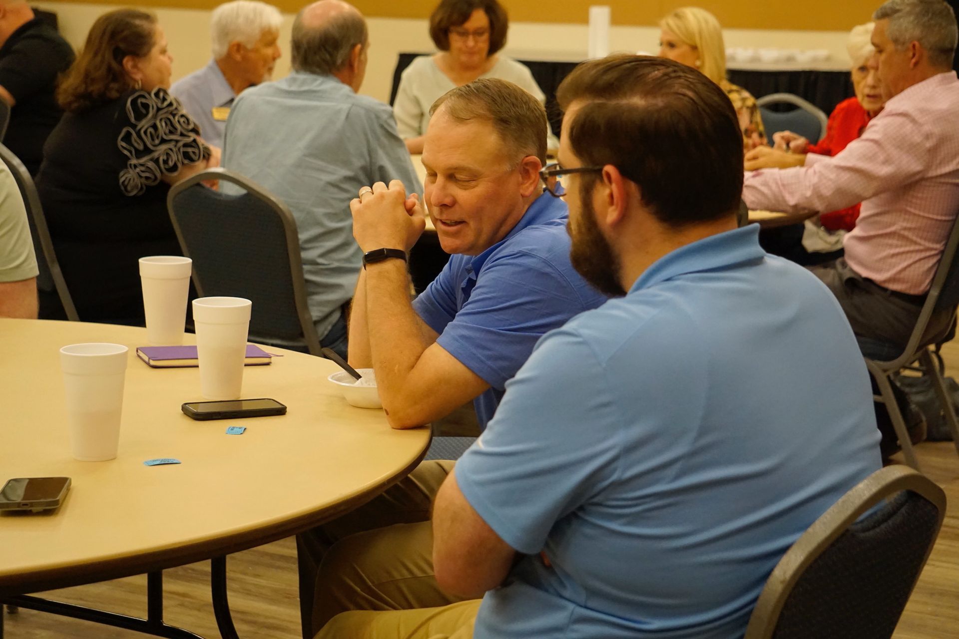 A group of people are sitting at tables talking to each other.