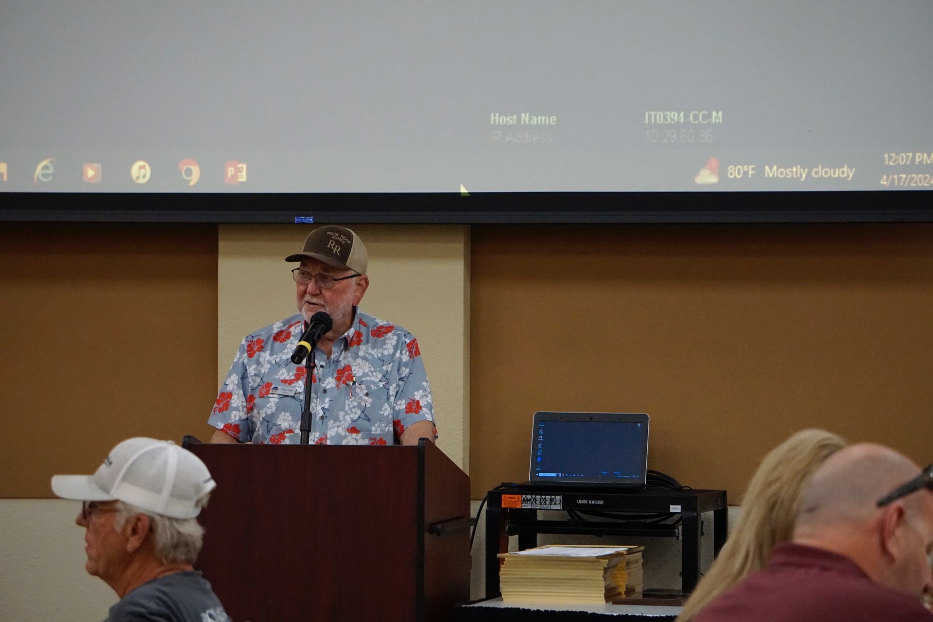 A man is standing at a podium talking into a microphone.