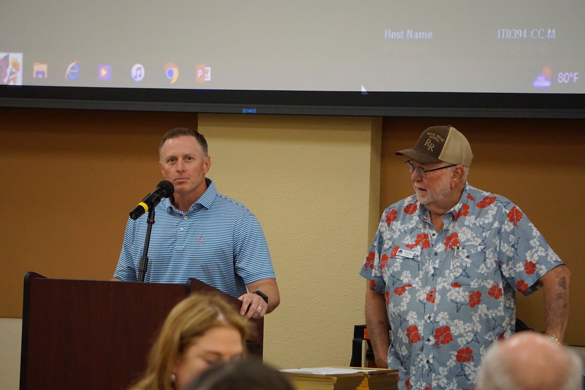 Two men are standing at a podium talking into microphones.