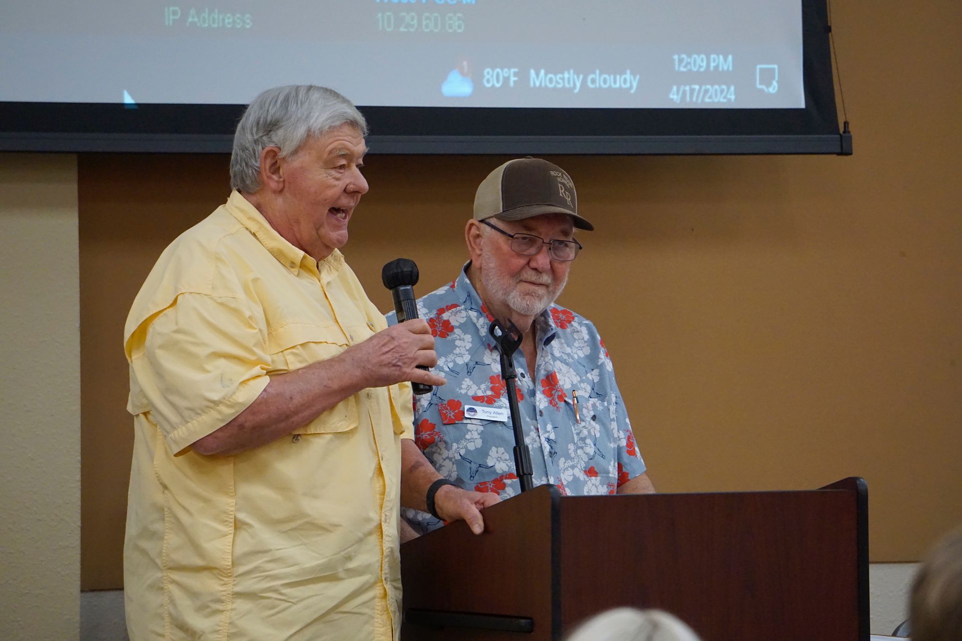 Two men are standing at a podium talking into microphones.