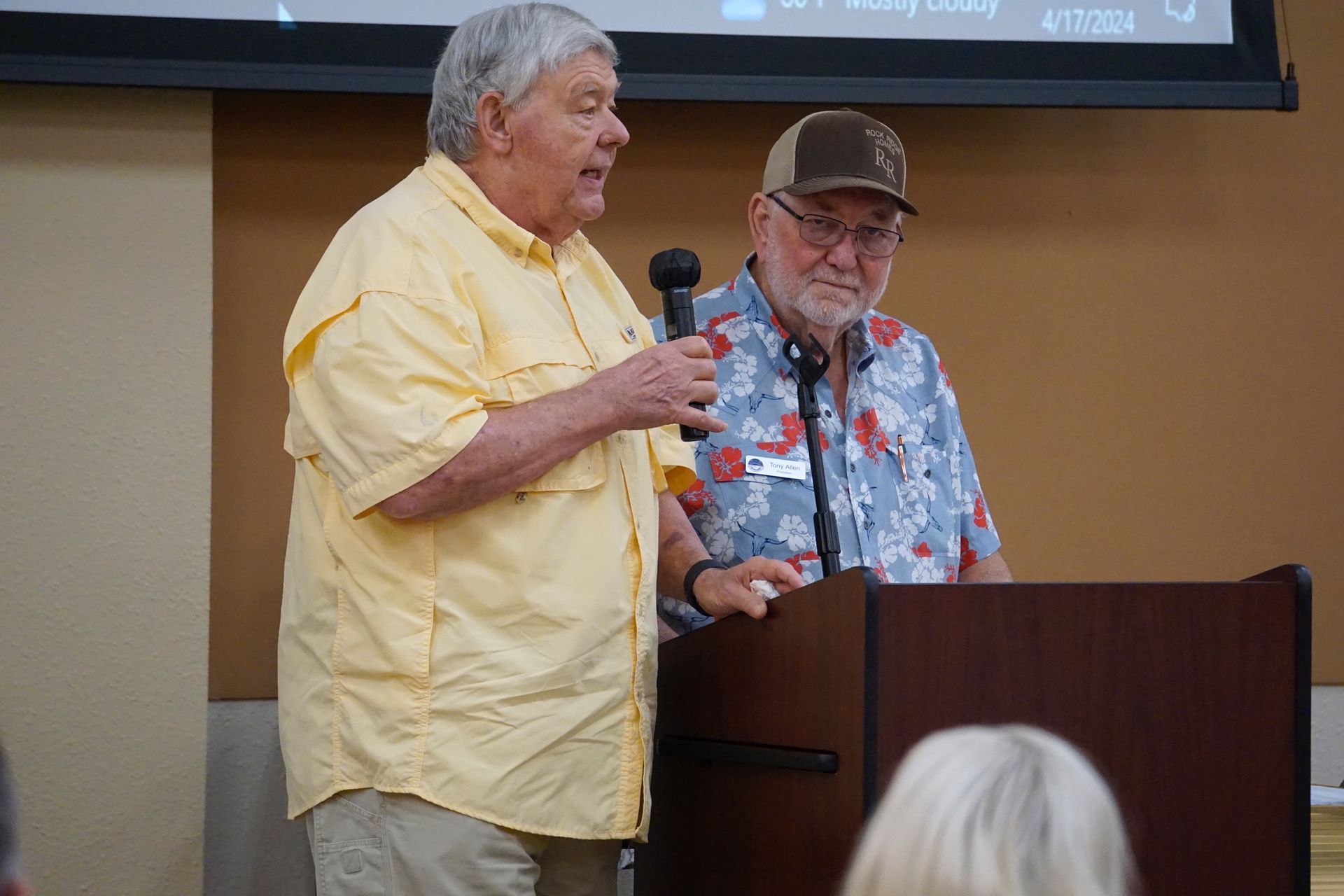 Two men are standing at a podium talking into microphones.