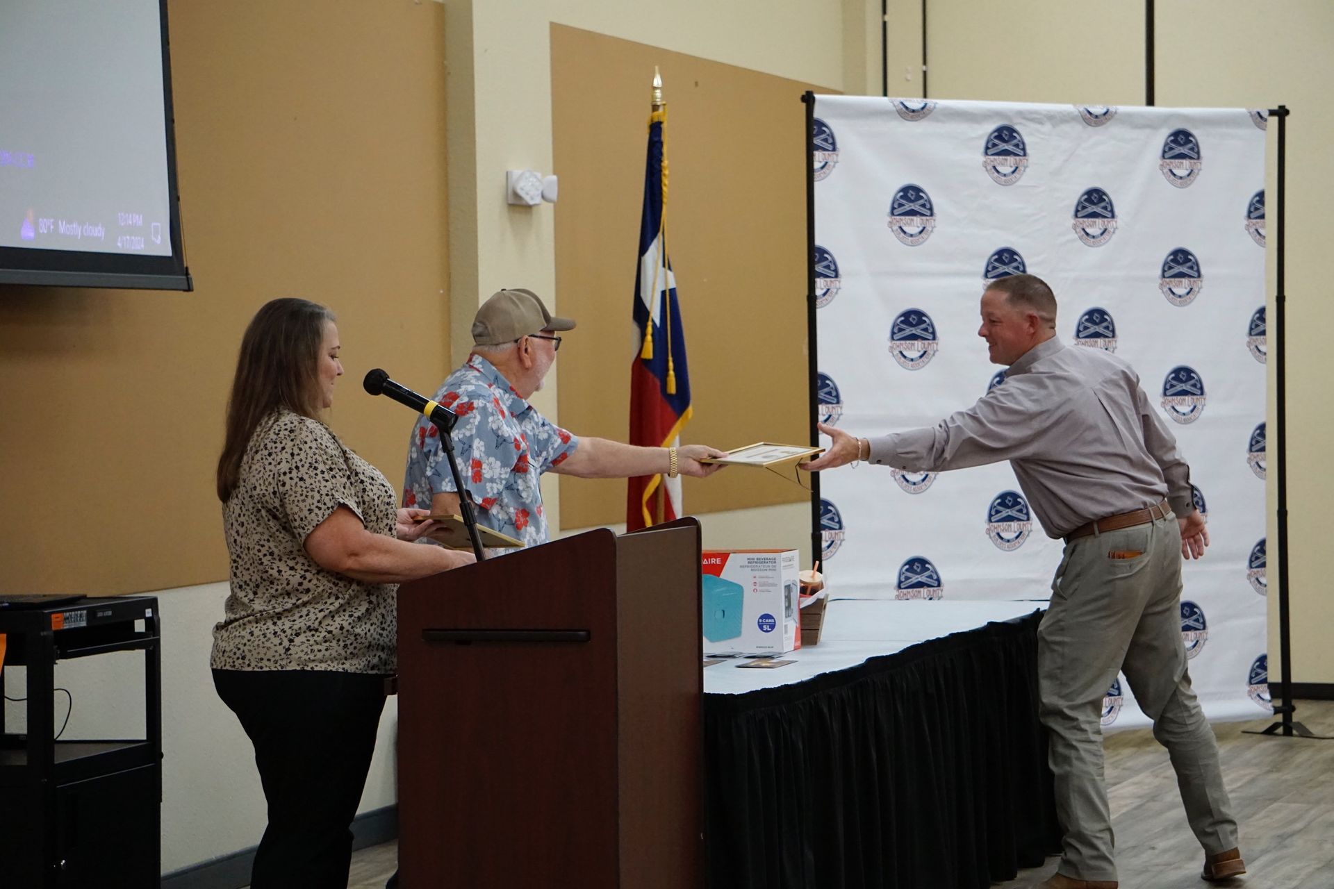 A man is giving a certificate to a woman at a podium.