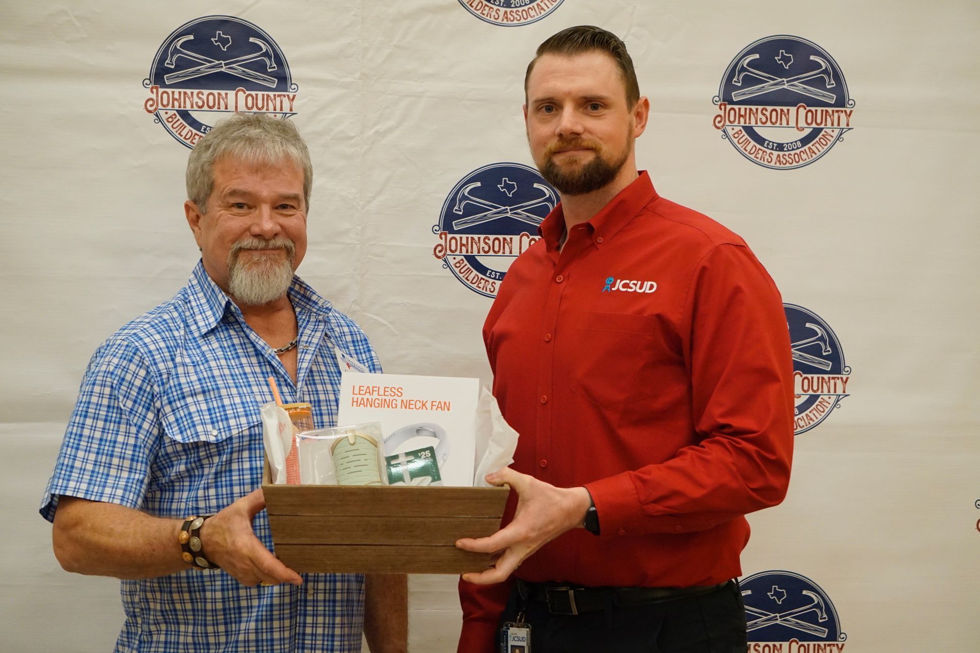 Two men are standing next to each other holding a box.