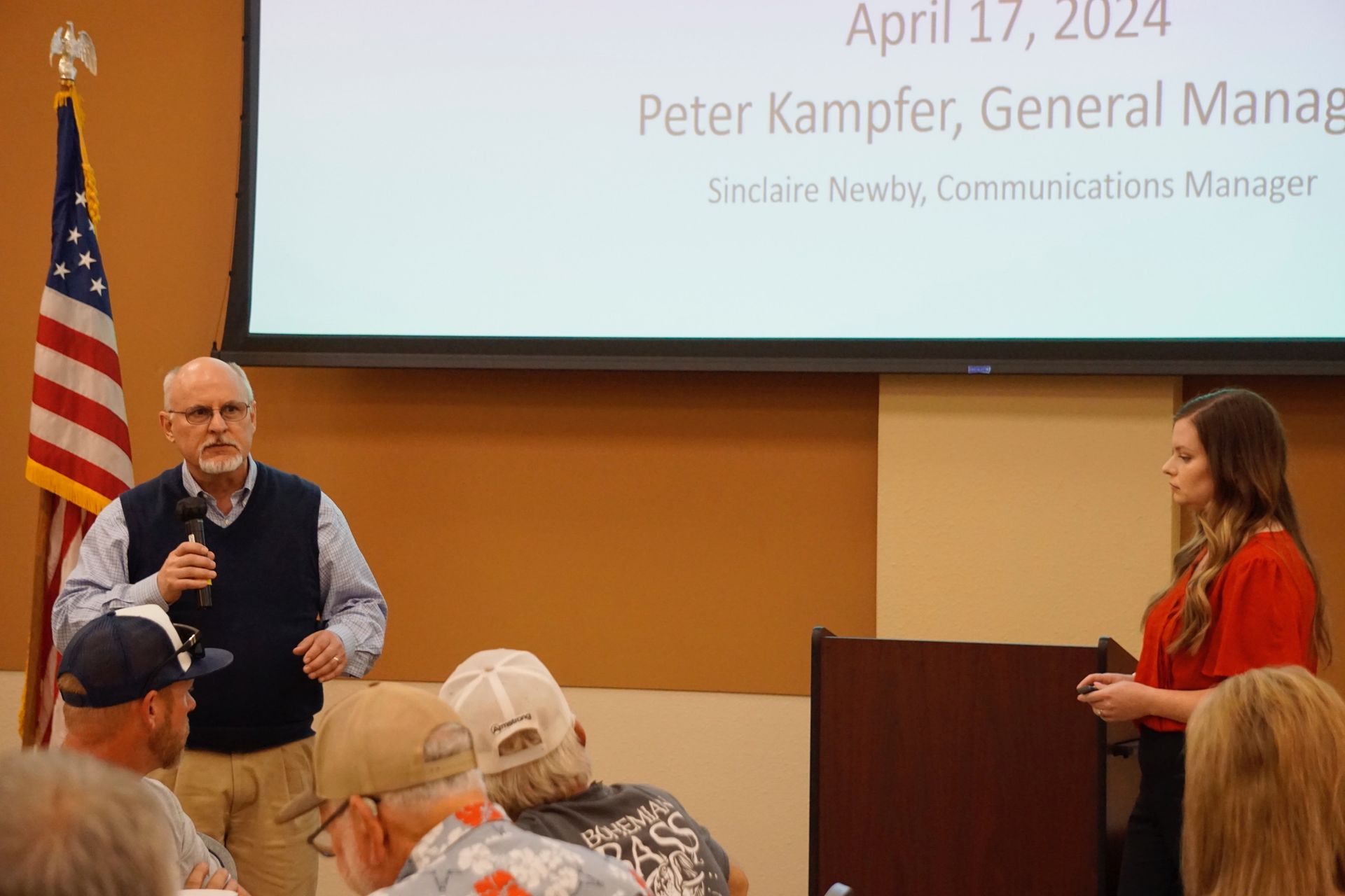 A man is giving a presentation to a group of people in front of a large screen.