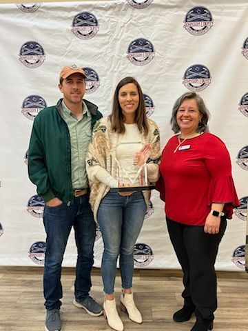 A man and two women are standing next to each other holding a trophy.