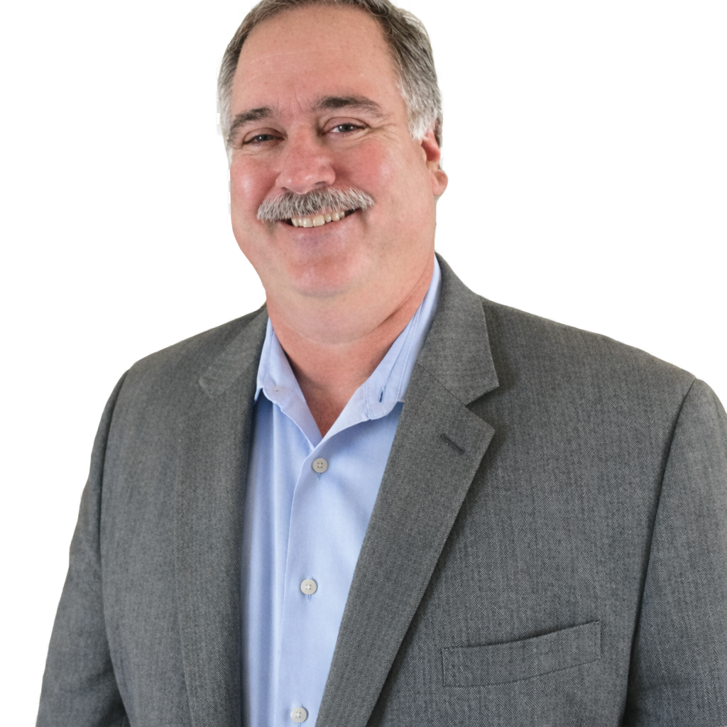 A man in a green shirt is sitting at a desk writing on a piece of paper