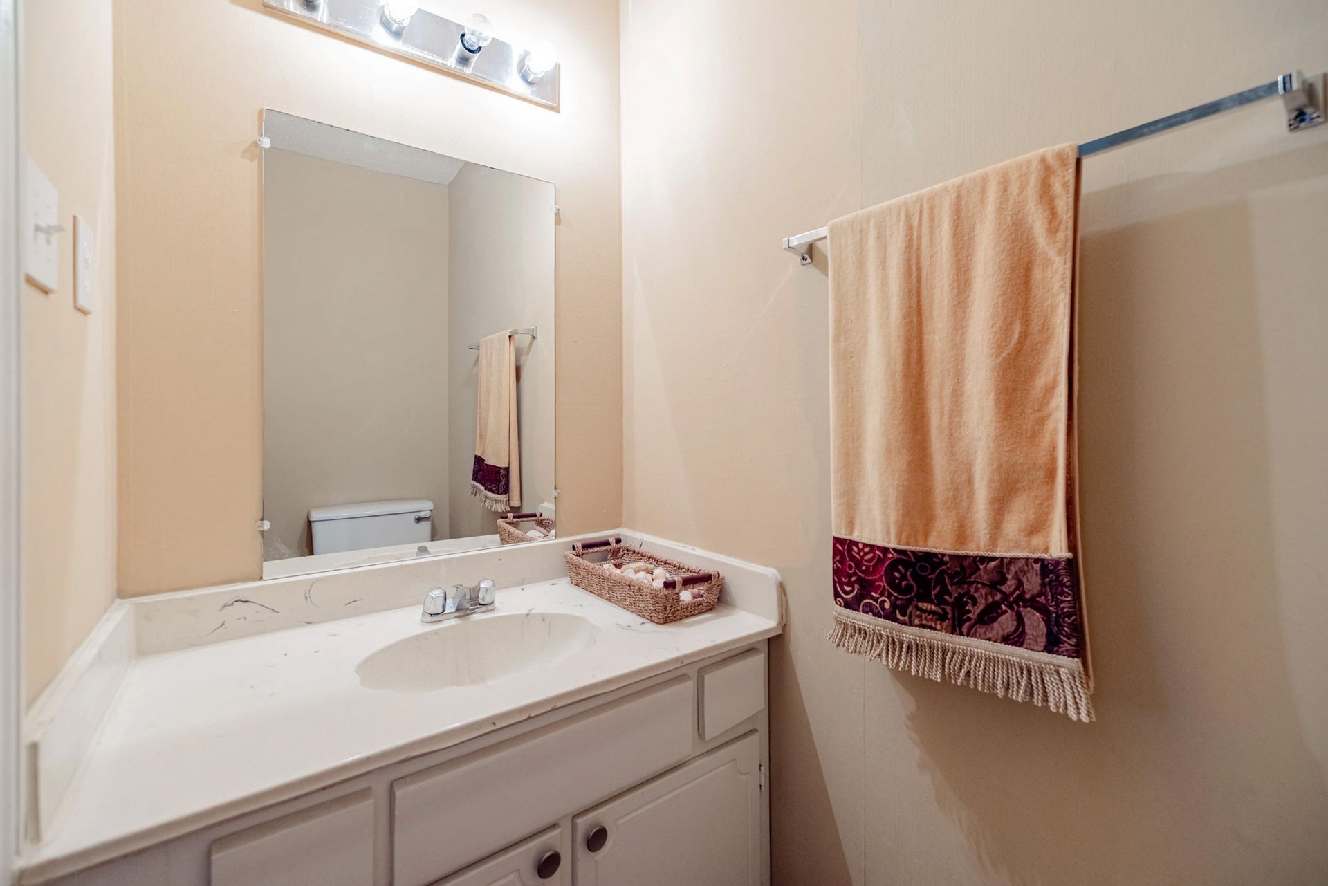 A bathroom with a sink , mirror and towel rack.