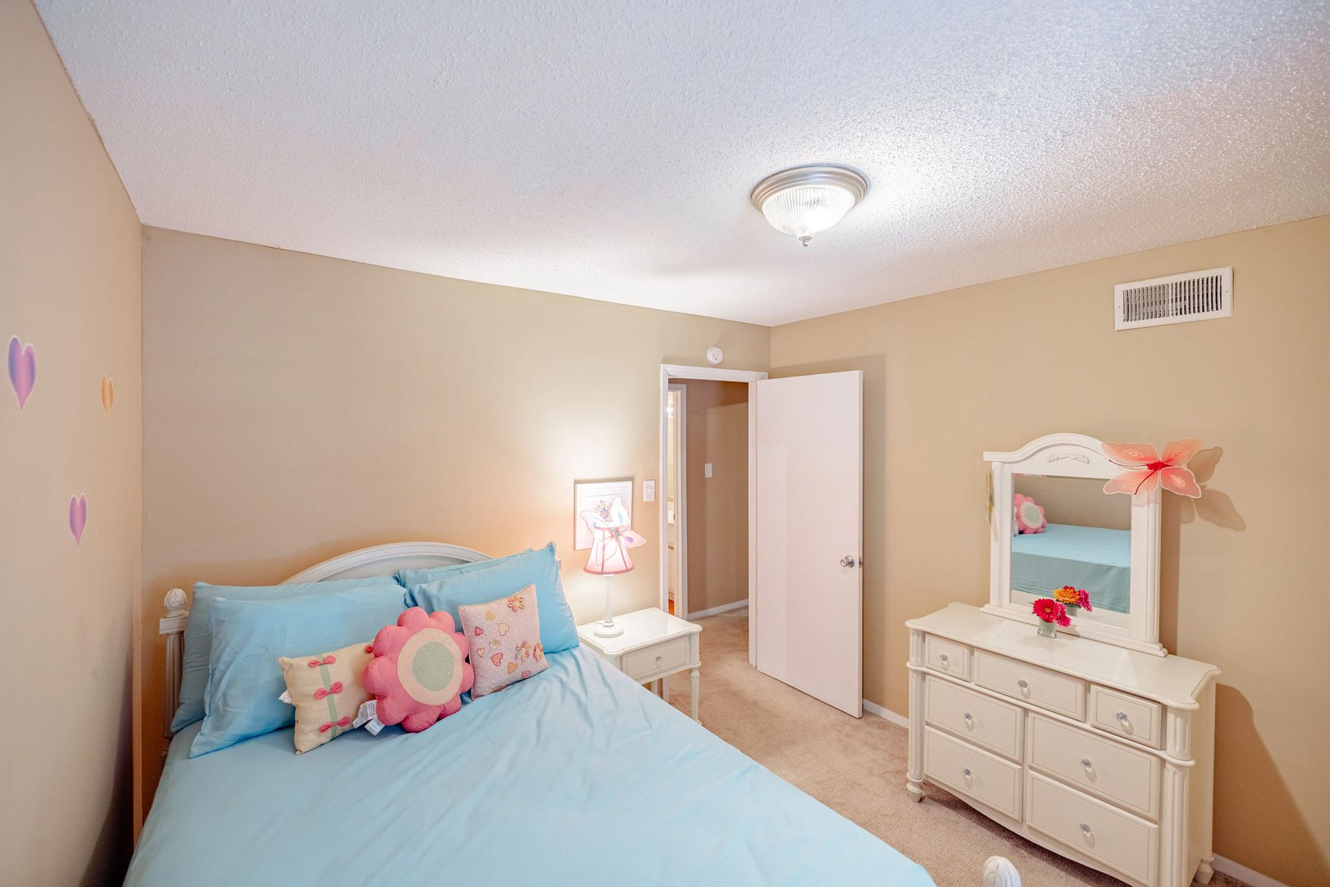 A bedroom with a bed , dresser and mirror.