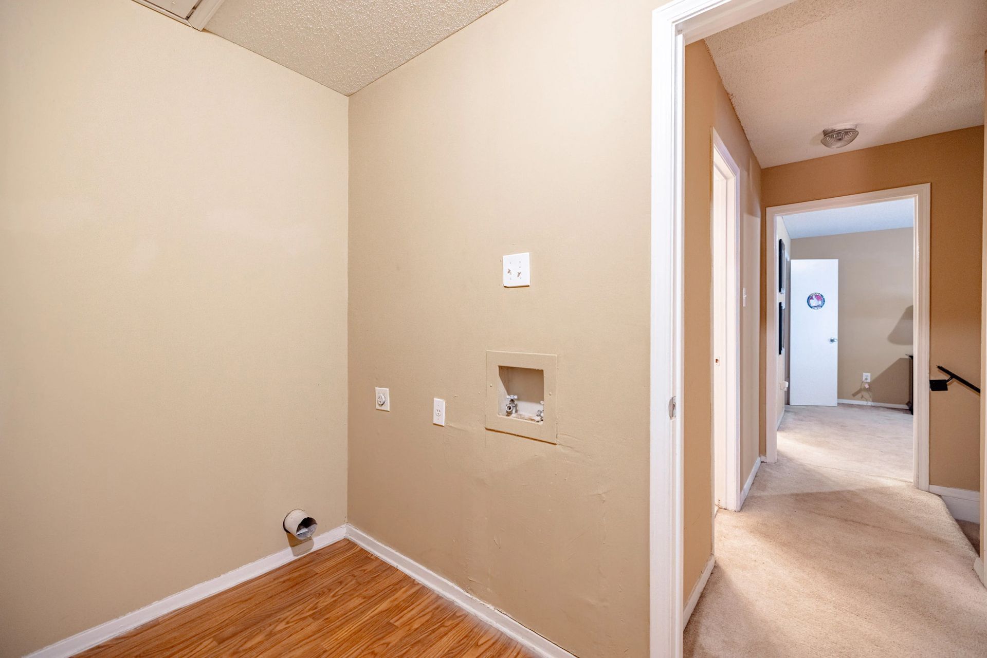 An empty laundry room in a house with a doorway leading to a hallway.
