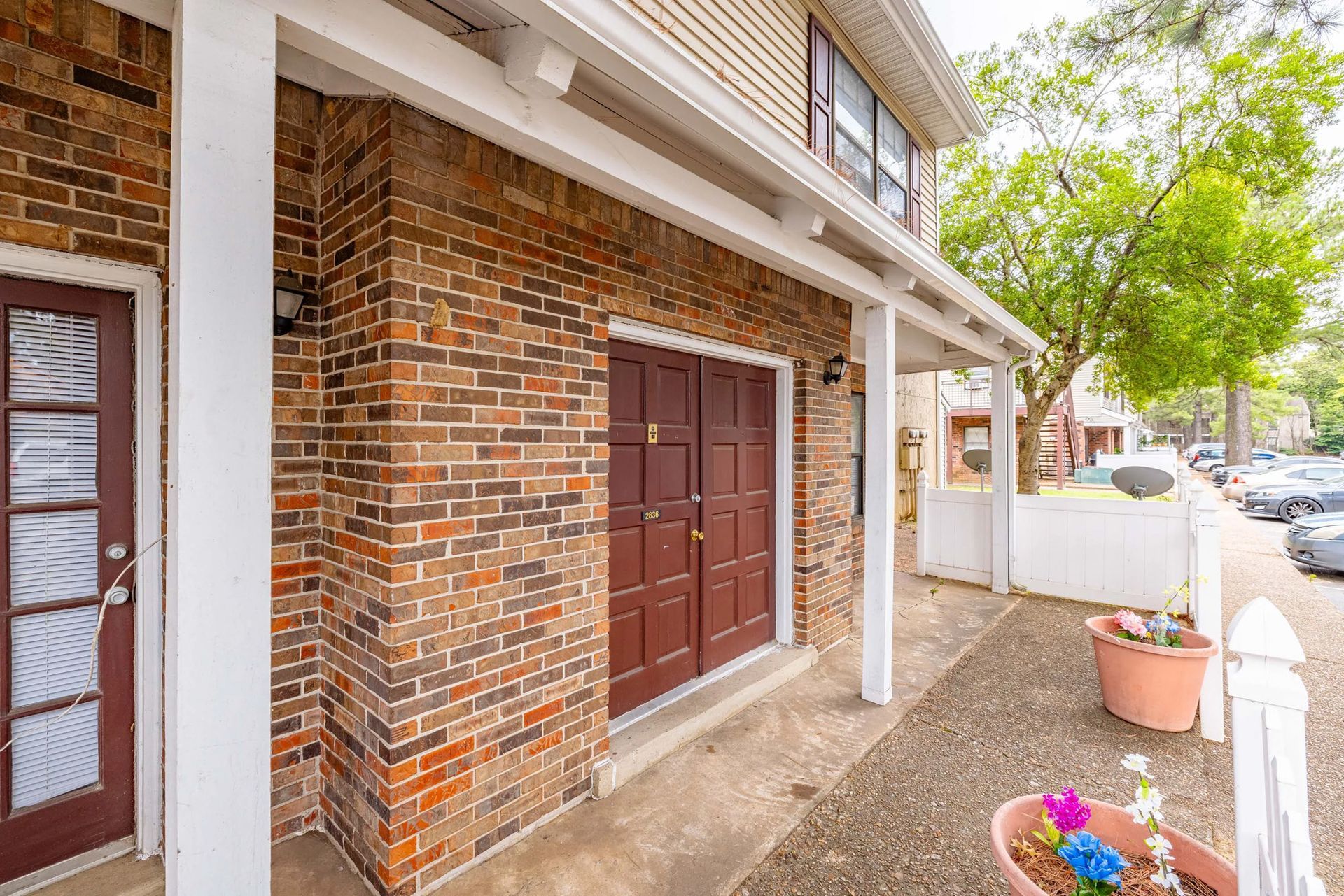 A brick building with two brown doors and a porch.