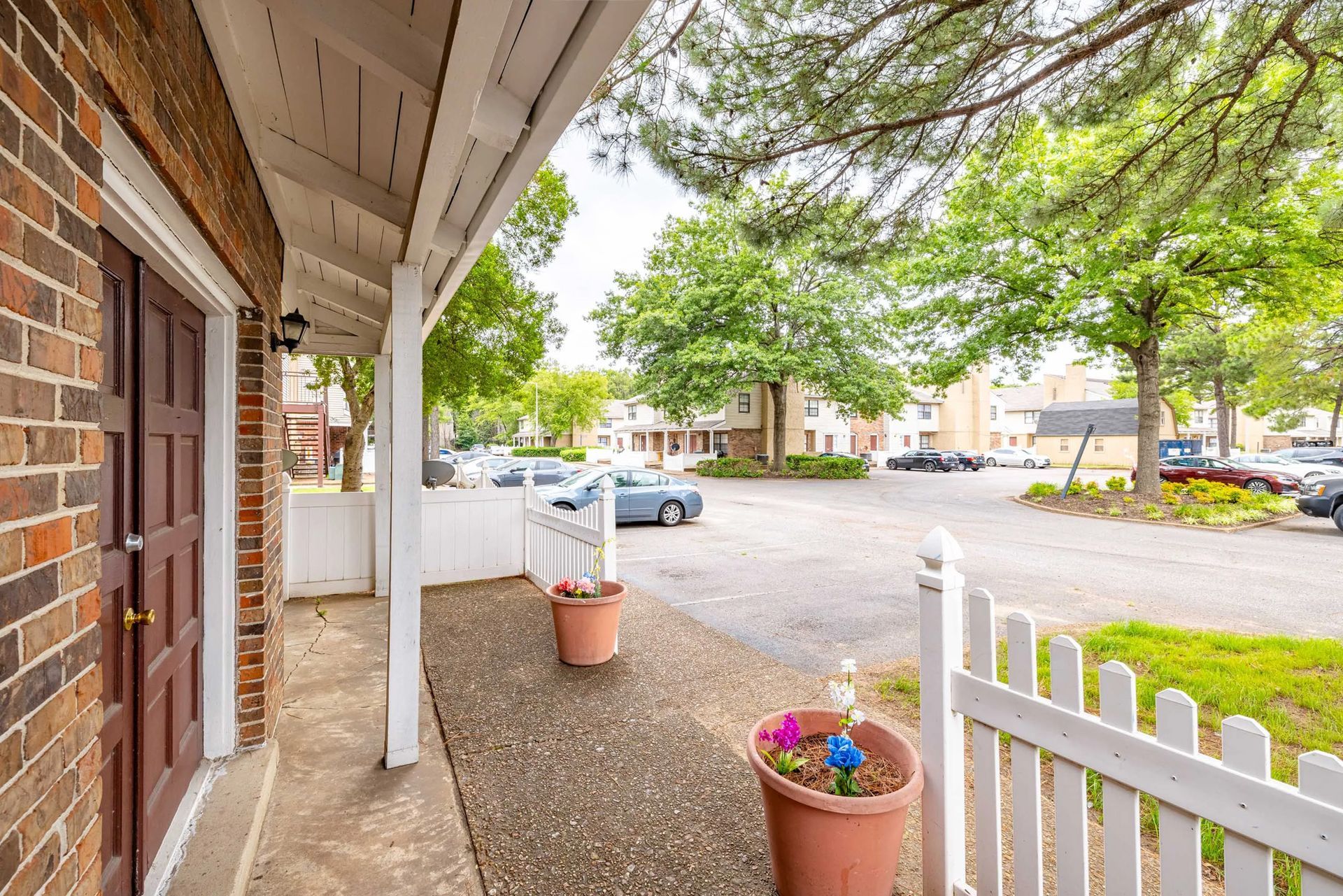 A brick building with a porch and a white picket fence.