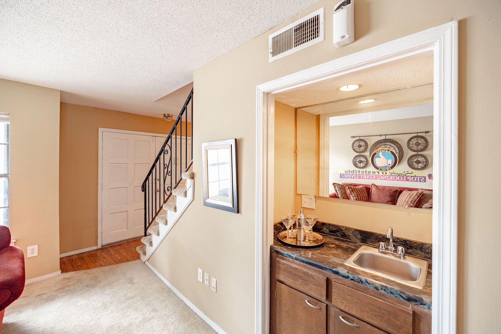 A bathroom with a sink , mirror and stairs in a house.