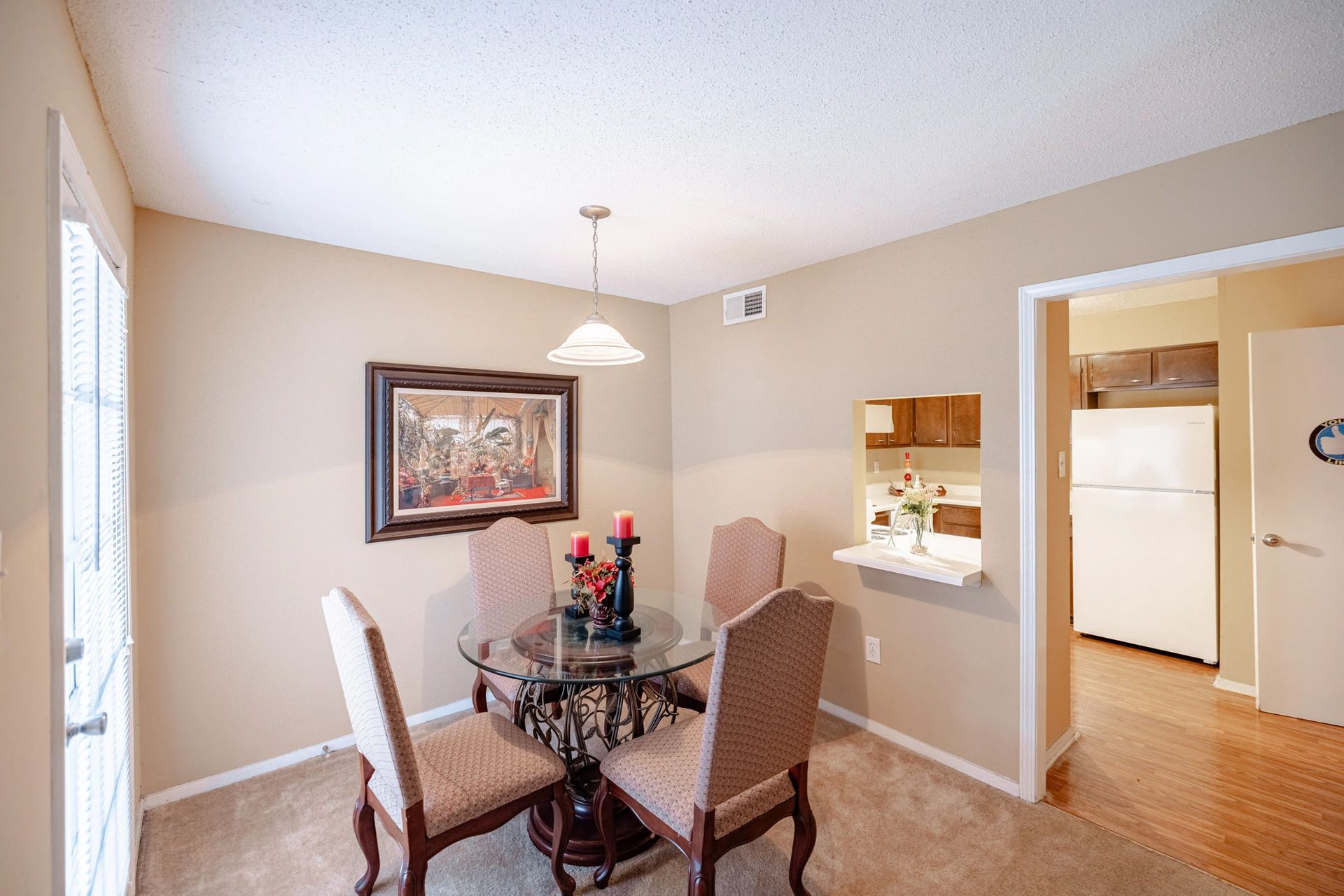 A dining room with a table and chairs and a refrigerator.